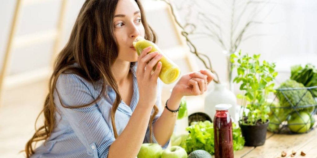 femeie bând un smoothie verde